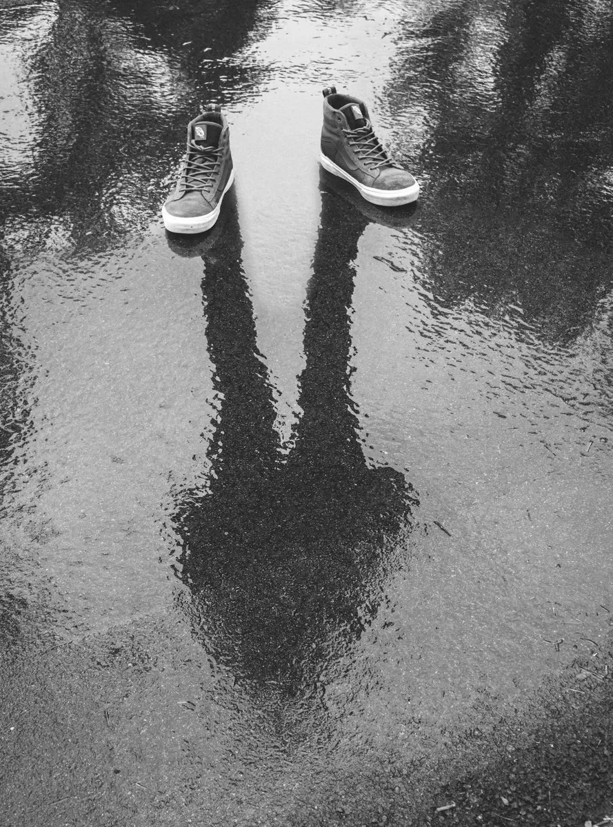 Shoes and a reflected silhouette on wet ground